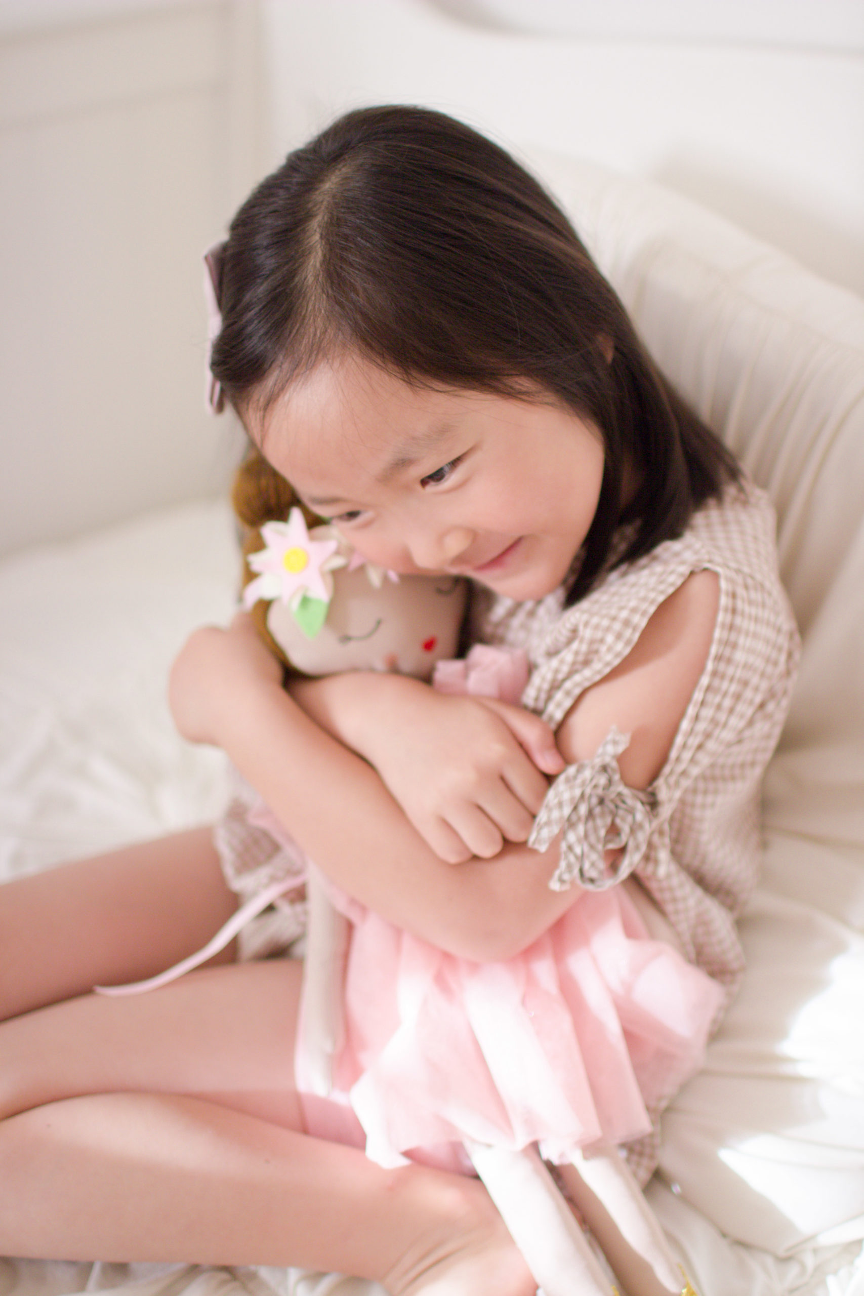 A little girl is embracing her doll, who is dark skinned. Photo taken by Tiffany Chi Photography.