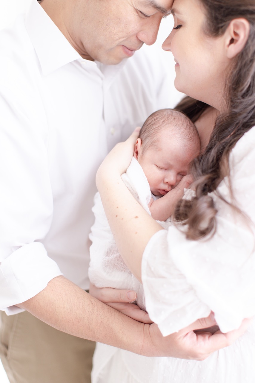 Newborn Baby in neutral all white studio with mother and father